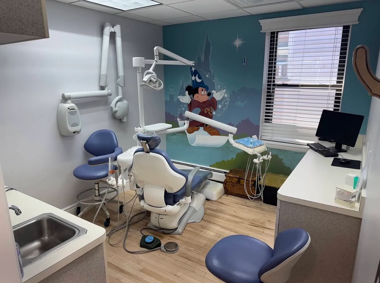 The children's treatment room with a painted wall mural and a blue dental chair.
