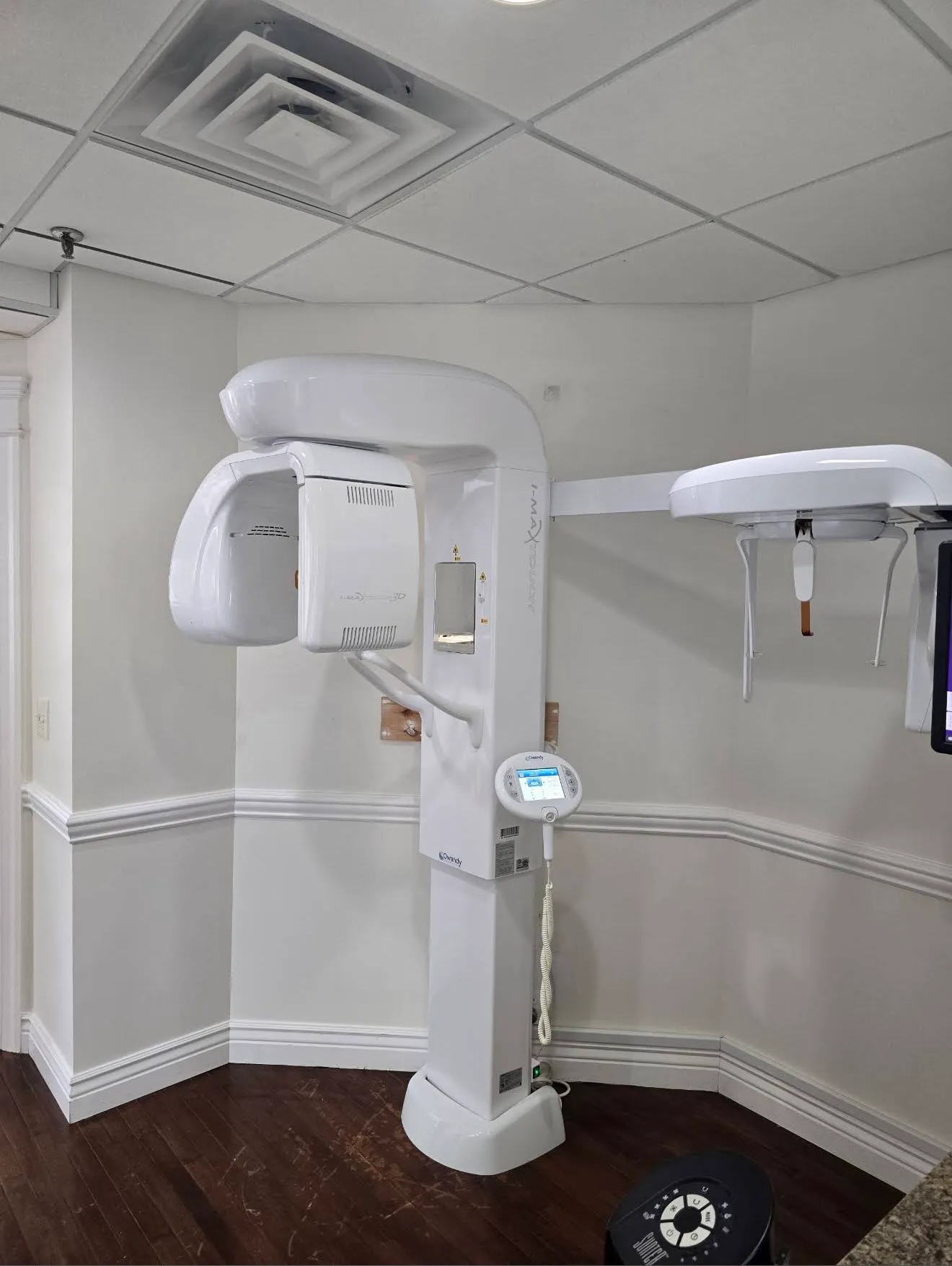 The imaging room with a wall-mounted Owandy panoramic X-ray unit and wainscoted walls.