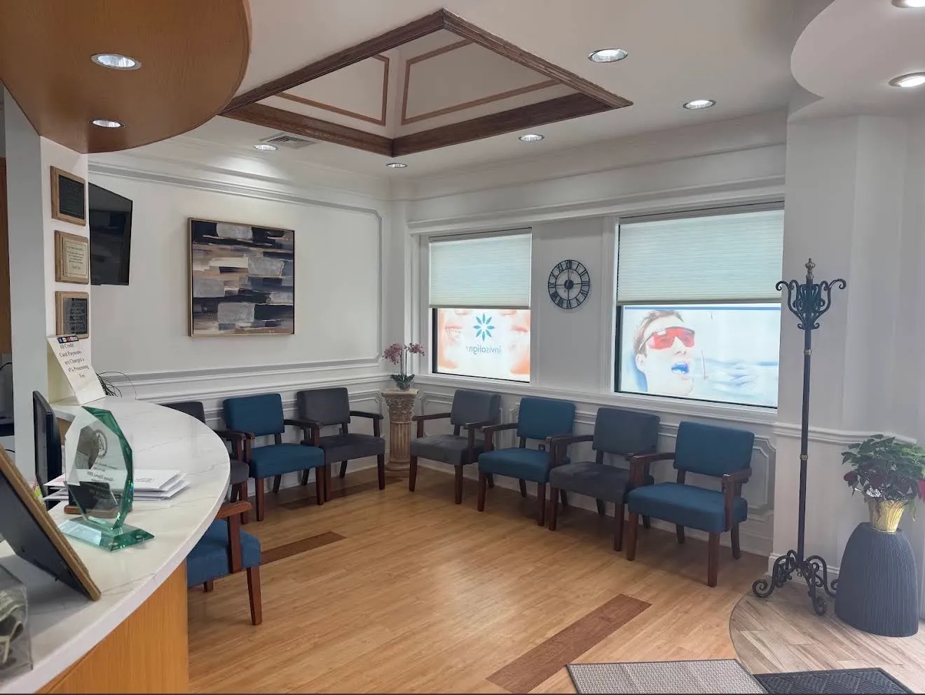 The waiting room: two rows of blue and grey armchairs along wainscoted walls under a coffered ceiling, with the reception counter at the left.