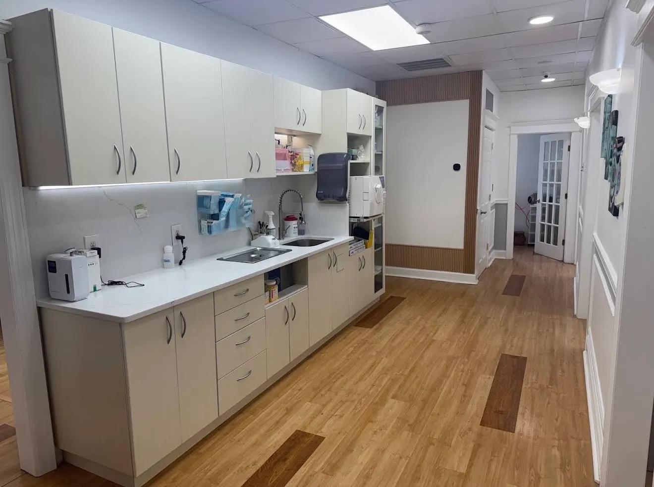 The sterilisation area: a long run of cabinets and counter with an autoclave and supplies, looking down the hallway towards the treatment rooms.