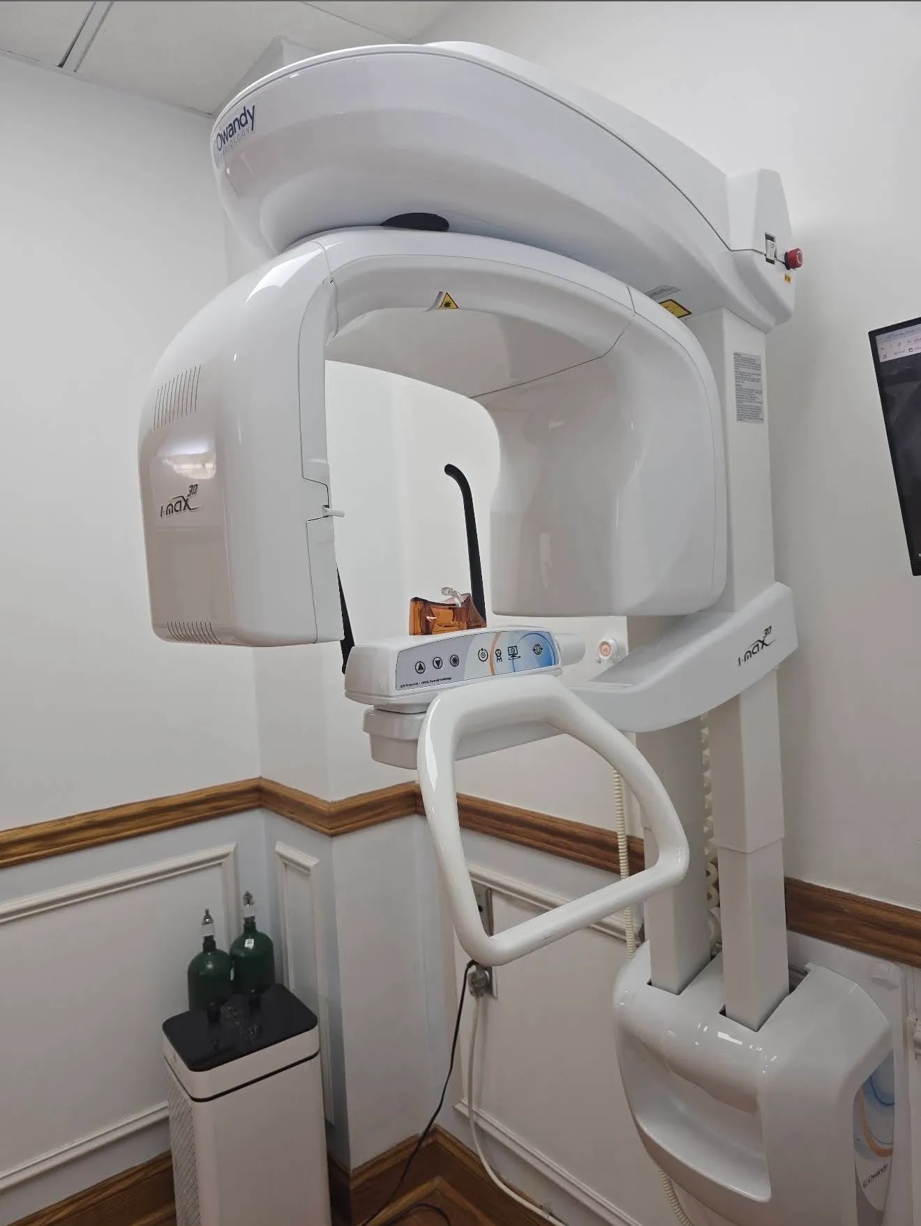 The panoramic X-ray unit seen from the doorway of the imaging room, with its bite guide and handrail at the centre.