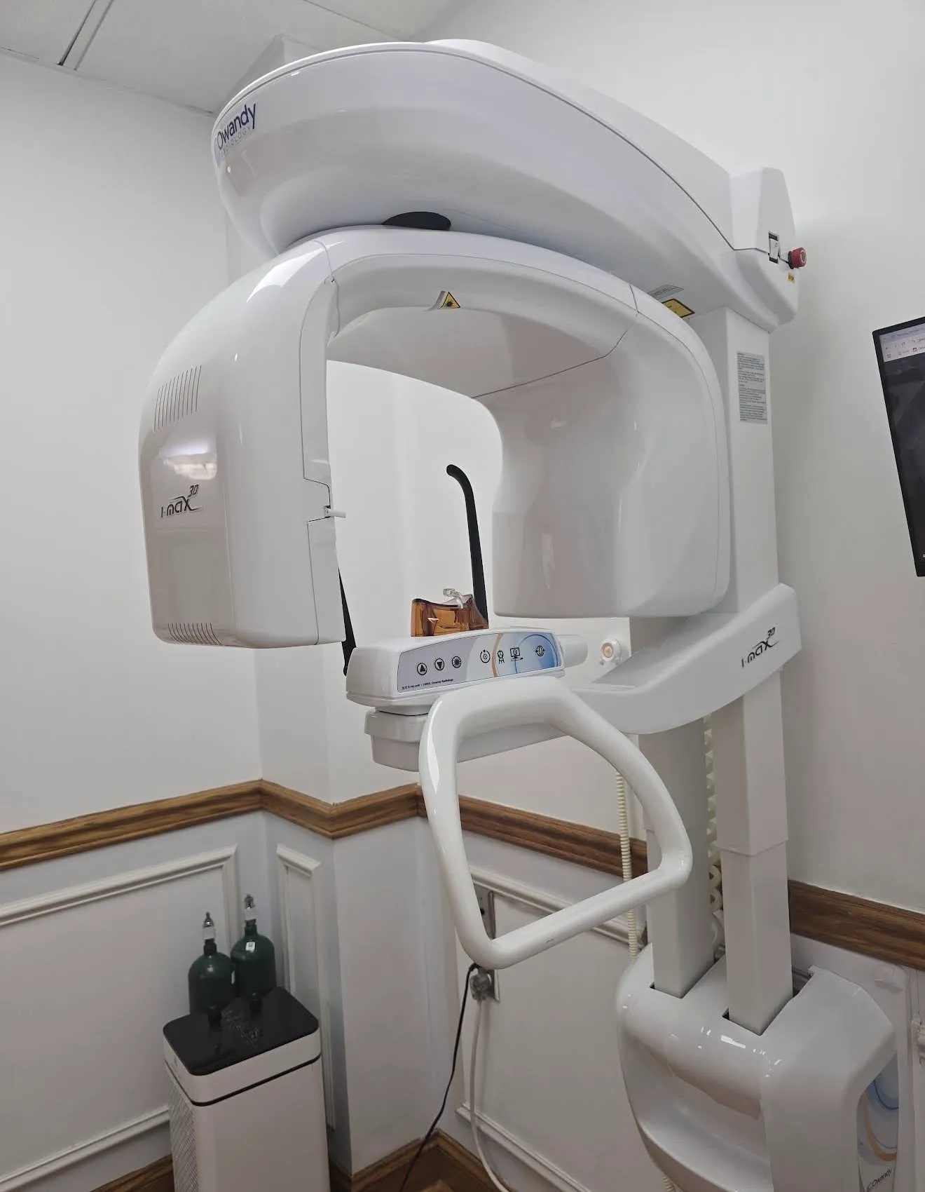 An Owandy i-Max 3D panoramic X-ray unit standing in the corner of a small imaging room.