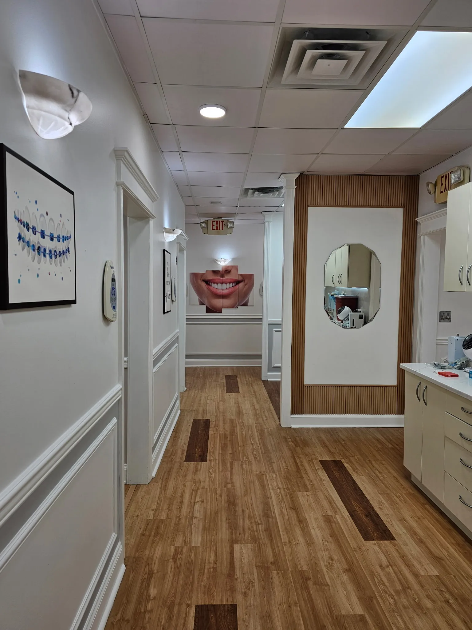 The treatment-room corridor, with framed dental artwork along the wall and a large smile photograph at the far end.
