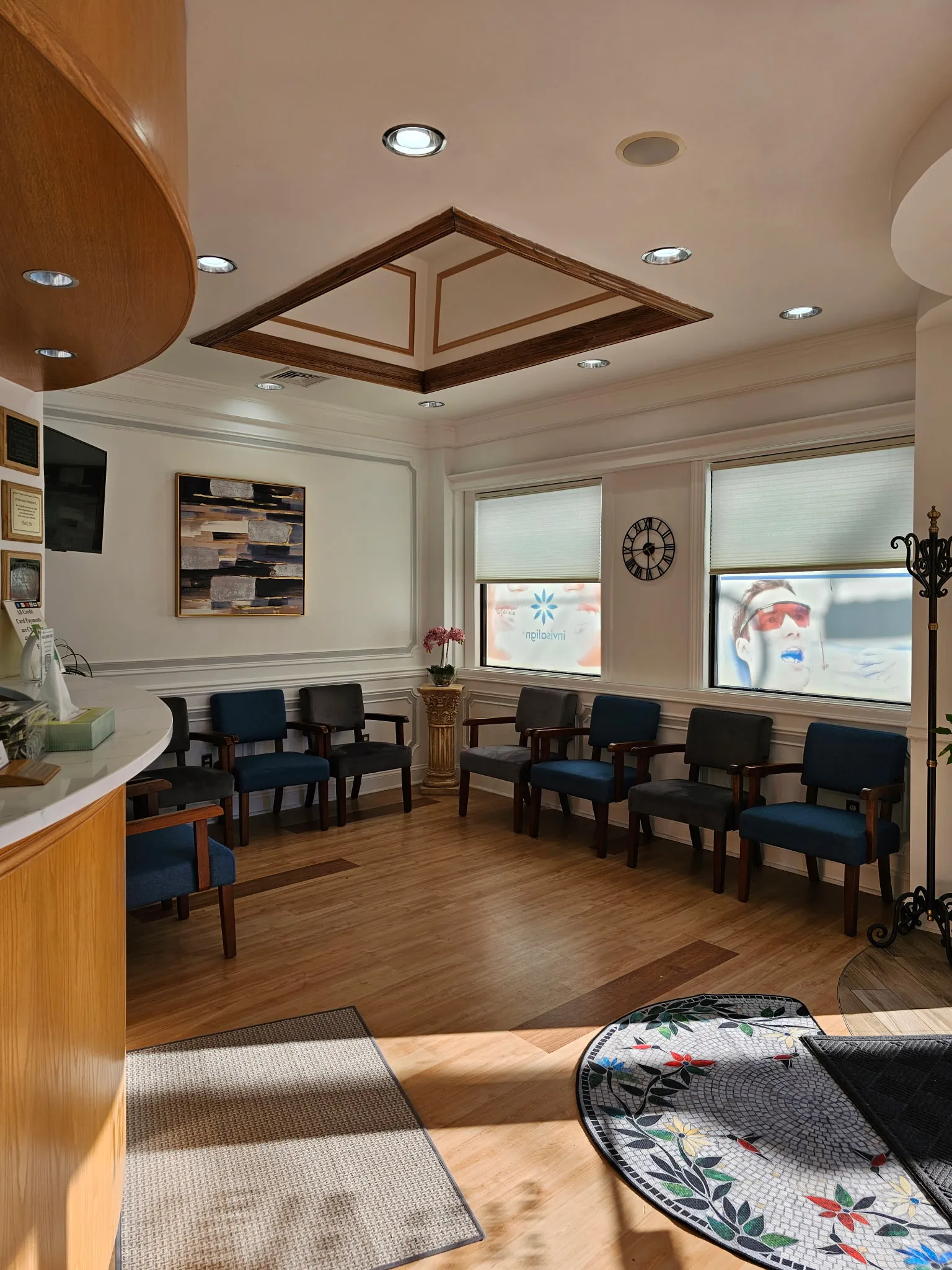 The waiting room, with seating for ten along two walls beneath shaded windows and a coffered wood ceiling.